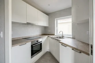 Cuisine équipée vide dans un appartement en location non meublée avec électroménager intégré et plans de travail en pierre
